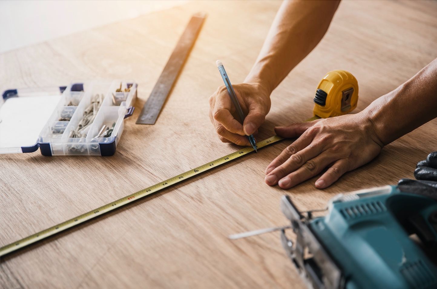 Carpenter measuring and marking a board with a square and tape measure