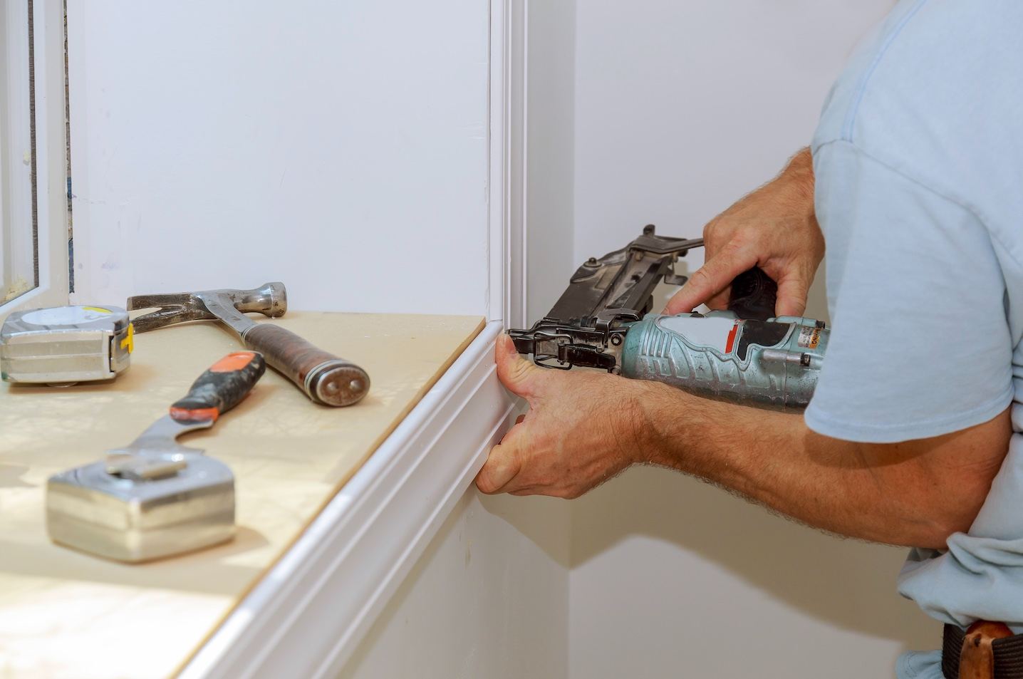 Carpenter installing window trim with a nail gun